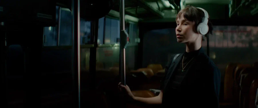 A person wearing headphones inside a dimly lit bus.